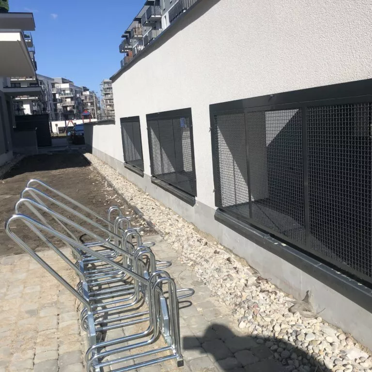 Szereg czarnych zabudów siatkowych wzdłuż budynku — realizacja Grid Poland