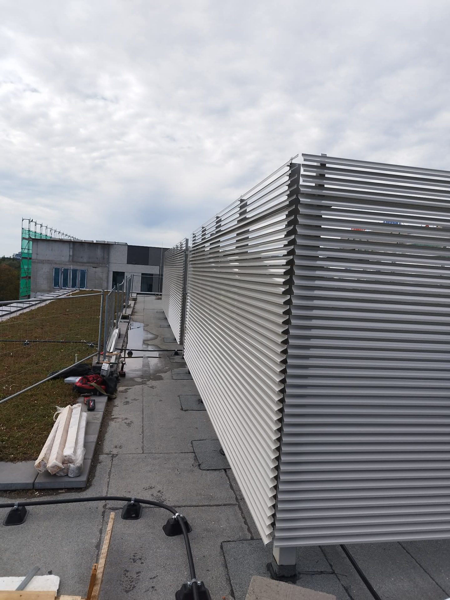 Jasnoszara zabudowa lamelowa wzdłuż dachu obiektu w budowie — realizacja Grid Poland
