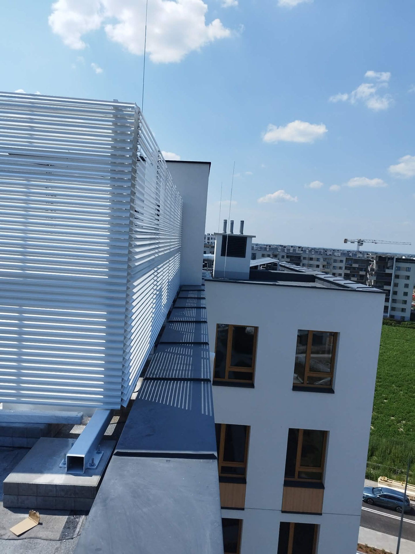 Biała zabudowa lamelowa urządzeń technicznych na dachu — realizacja Grid Poland