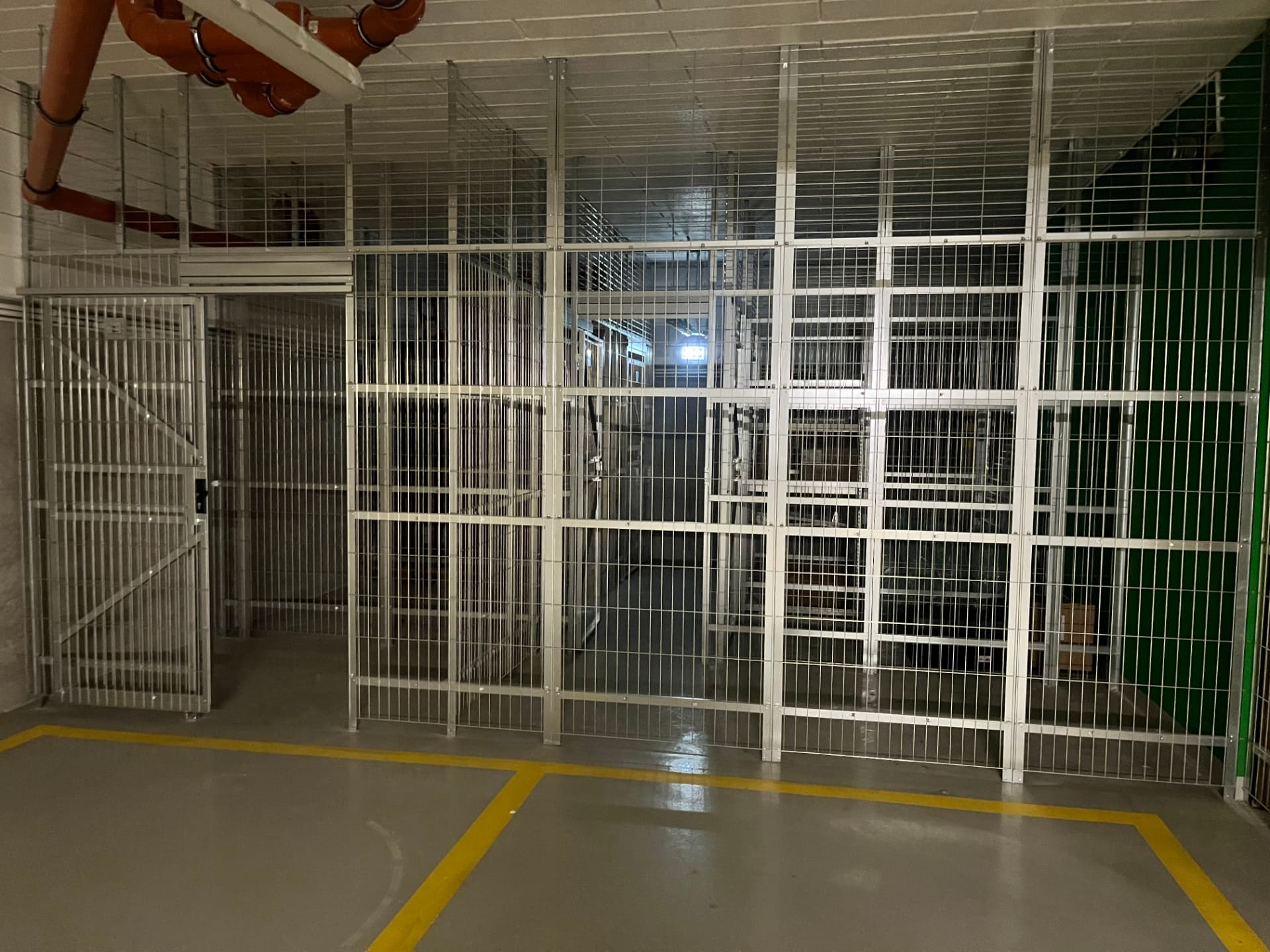 Rząd komórek lokatorskich z siatki zgrzewanej wzdłuż ściany garażu — realizacja Grid Poland