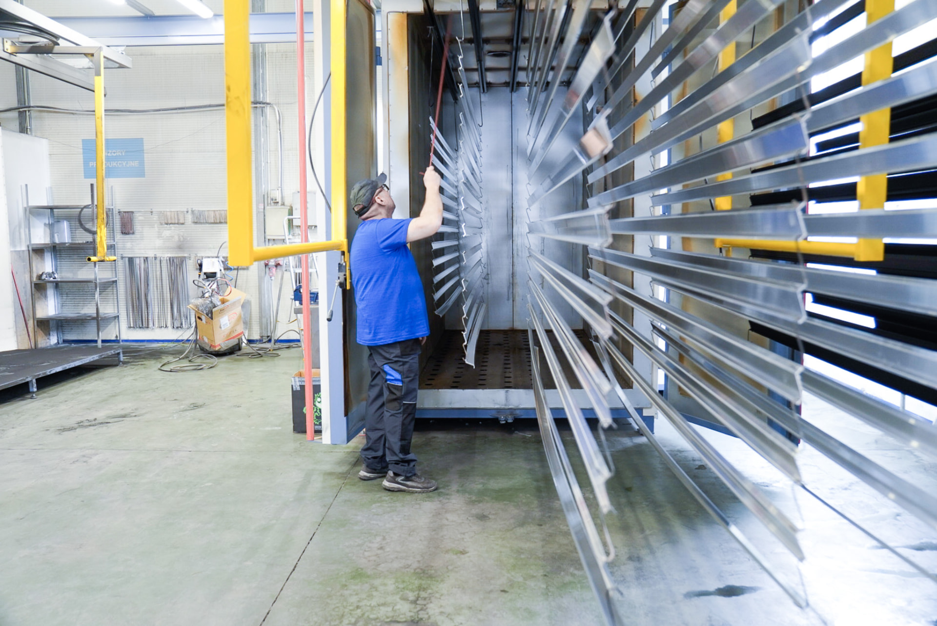 Operator wprowadza profile aluminiowe do pieca lakierniczego w Grid Poland